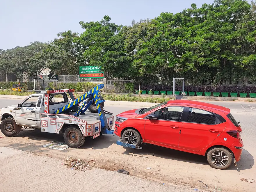 Tow truck towing a red hatchback in Hyderabad