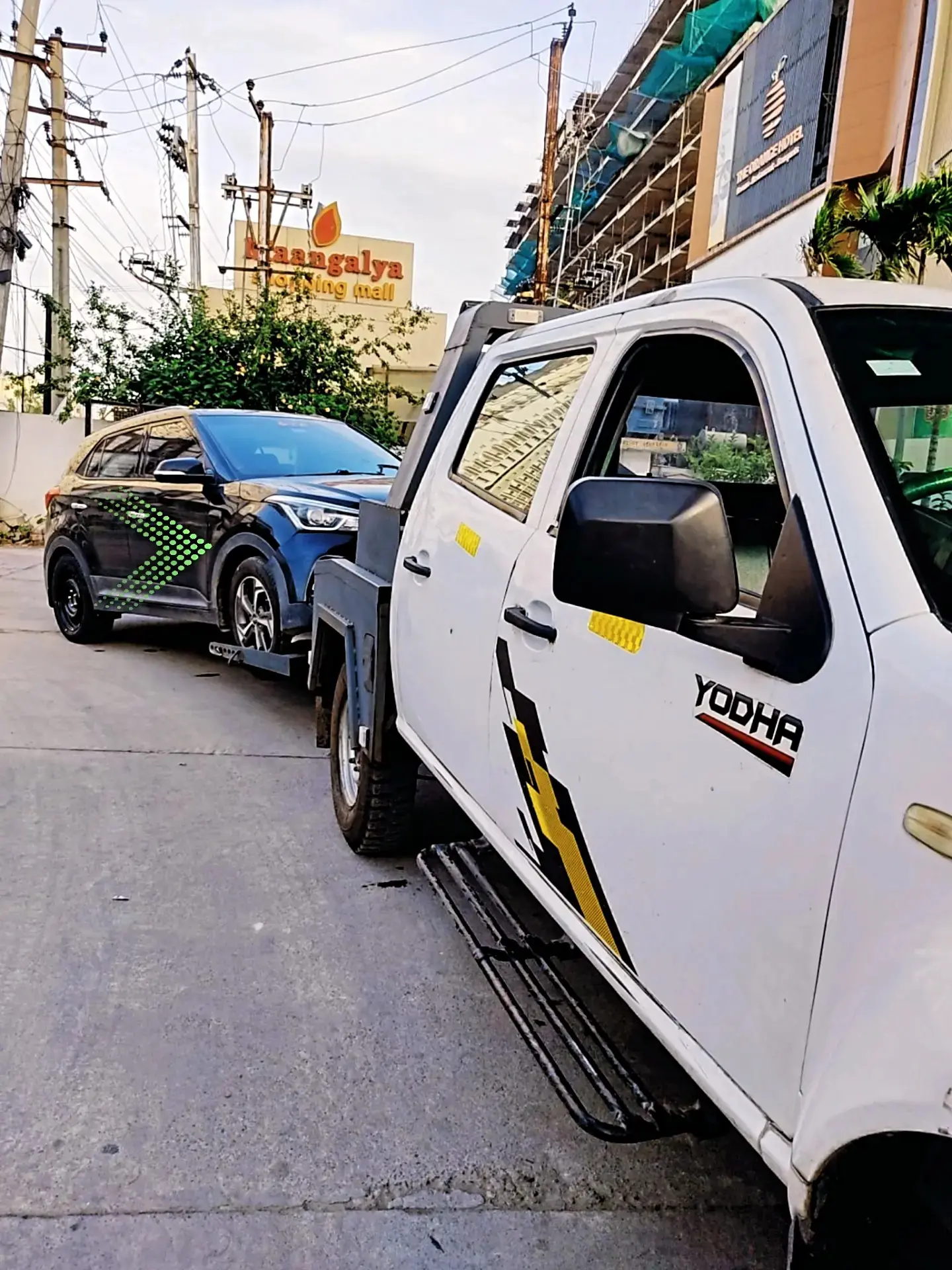 Tow truck lifting a car on a narrow Hyderabad street