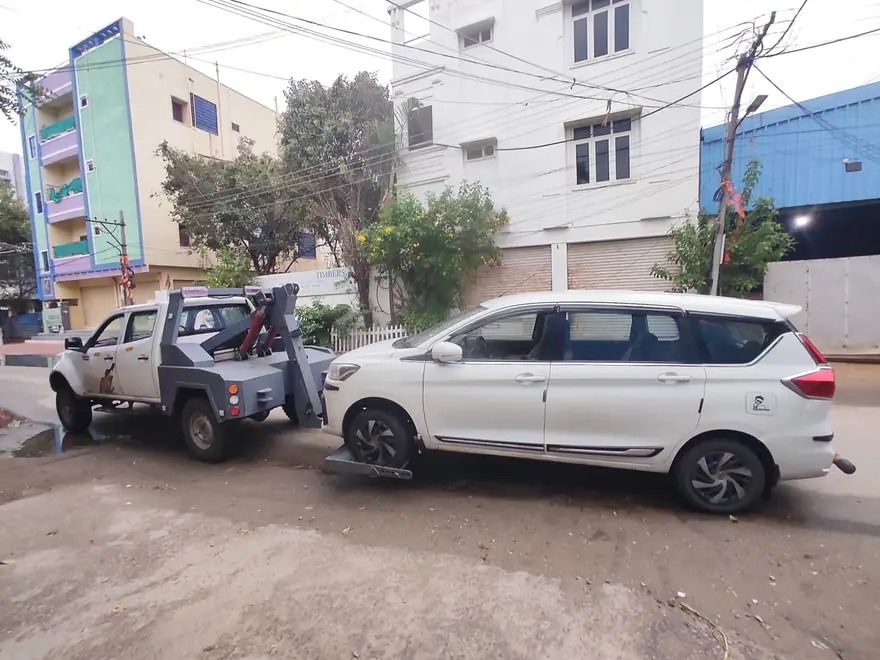 Tow truck towing a white MPV on a Hyderabad street